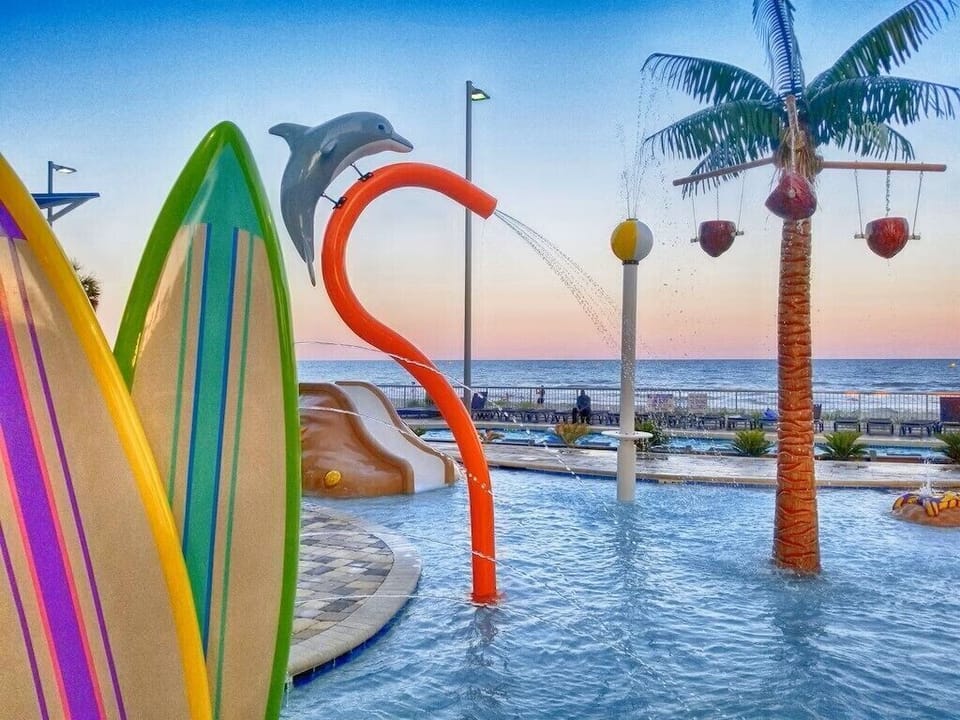 Vibrant splash area with waterfall, fountains, sculptures & ocean views