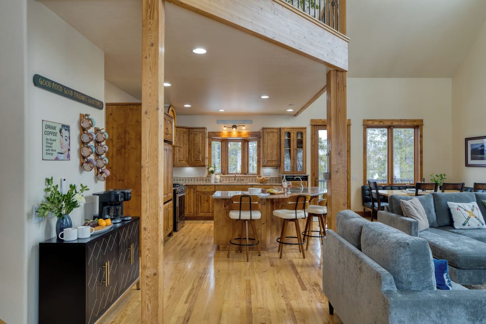 Open-concept living space showing the high ceiling, plush sofa, card table, and modern appliances.