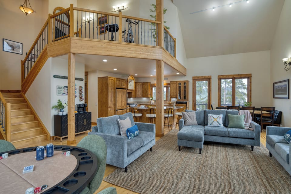 Open-concept living space showing the high ceiling, plush sofa, card table, and modern appliances.