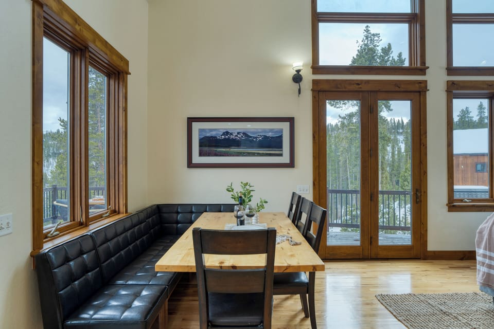 Dining area with a long table next to large windows.