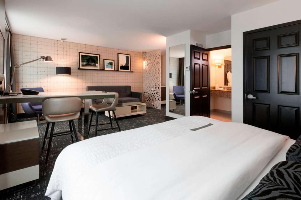 Room with plush bed, work desk, sofa, and framed wall art
