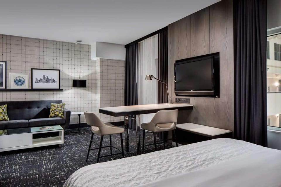 Desk and chairs near bed, TV, and a cozy couch with pillows
