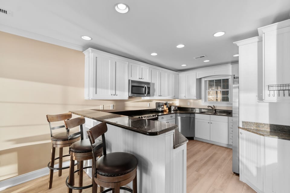 Your spacious kitchen features granite countertops, stainless steel appliances, and a convenient breakfast bar perfect for morning coffee.