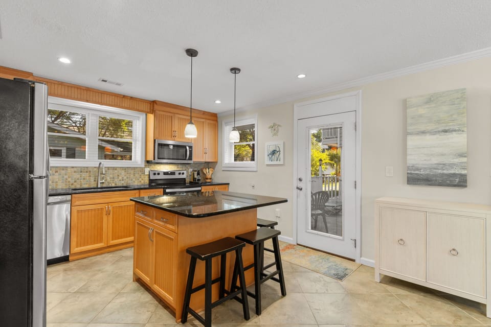 Your fully-equipped kitchen awaits with warm wood cabinets, granite countertops, and a convenient island perfect for morning coffee or meal prep.