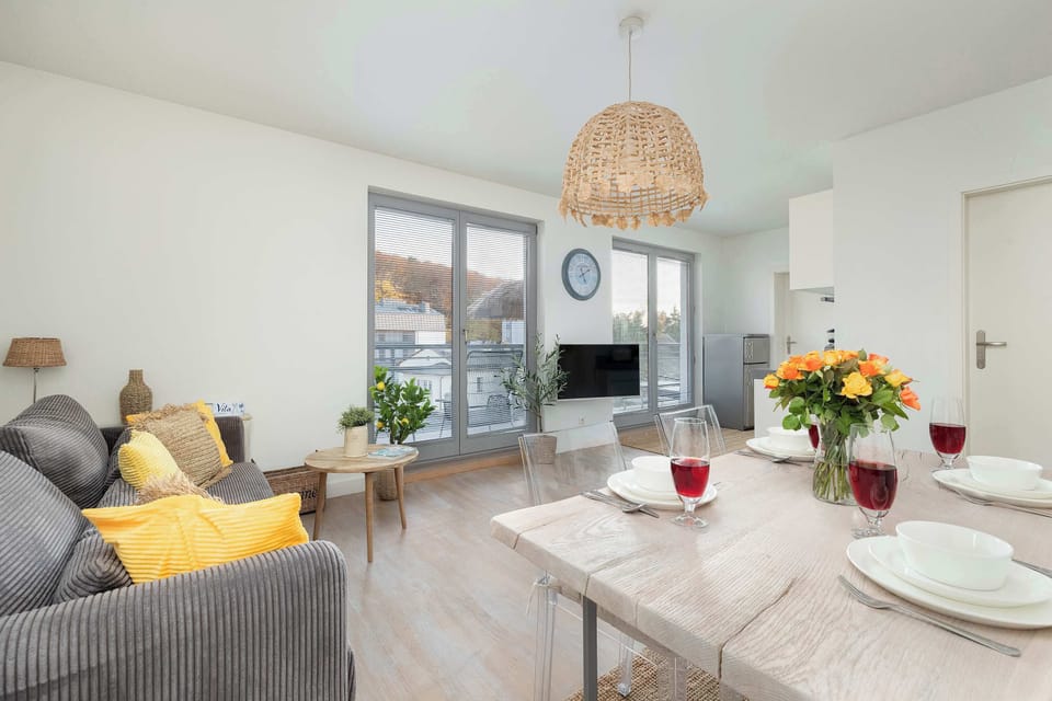 A spacious living room with a sofa, rug, and large windows bringing in daylight.