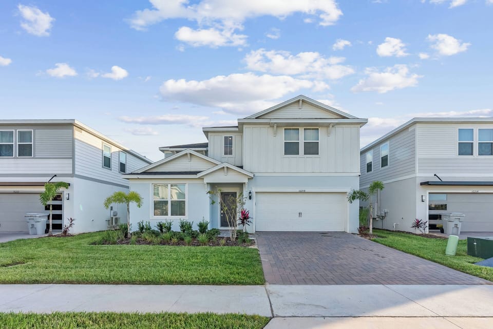 This charming vacation home features a bright exterior with clean lines and lovely landscaping. The inviting front porch, surrounded by greenery, creates a welcoming atmosphere for a comfortable and memorable stay.