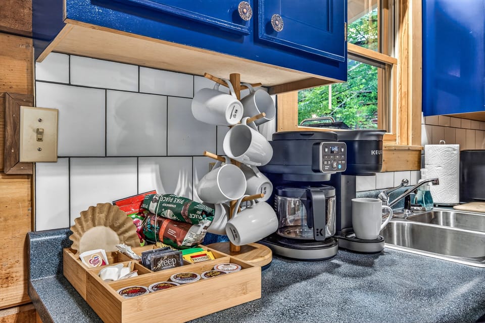 Charming kitchen coffee station with stocked mugs and wooded views