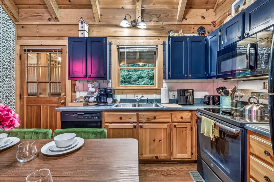Rustic-modern kitchen with navy cabinets, full appliances, and cozy dining space