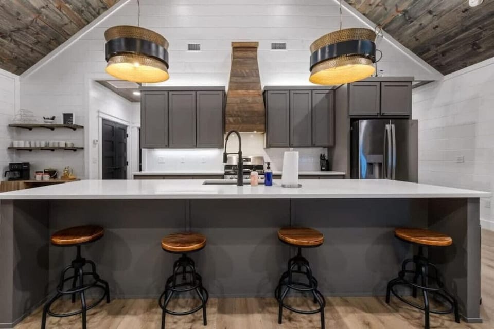 Modern kitchen with quartz island, stainless appliances, and stylish lighting.