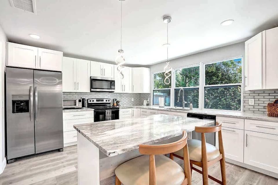 Bright white kitchen with marble island and stainless appliances