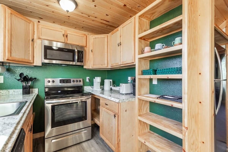 Fully stocked kitchen with pots and pans, griddle, baking sheets, muffin tins, blender, mugs, dinnerware, silverware, knifes, spatulas, electric handmixer, toaster, and electric water kettle. 