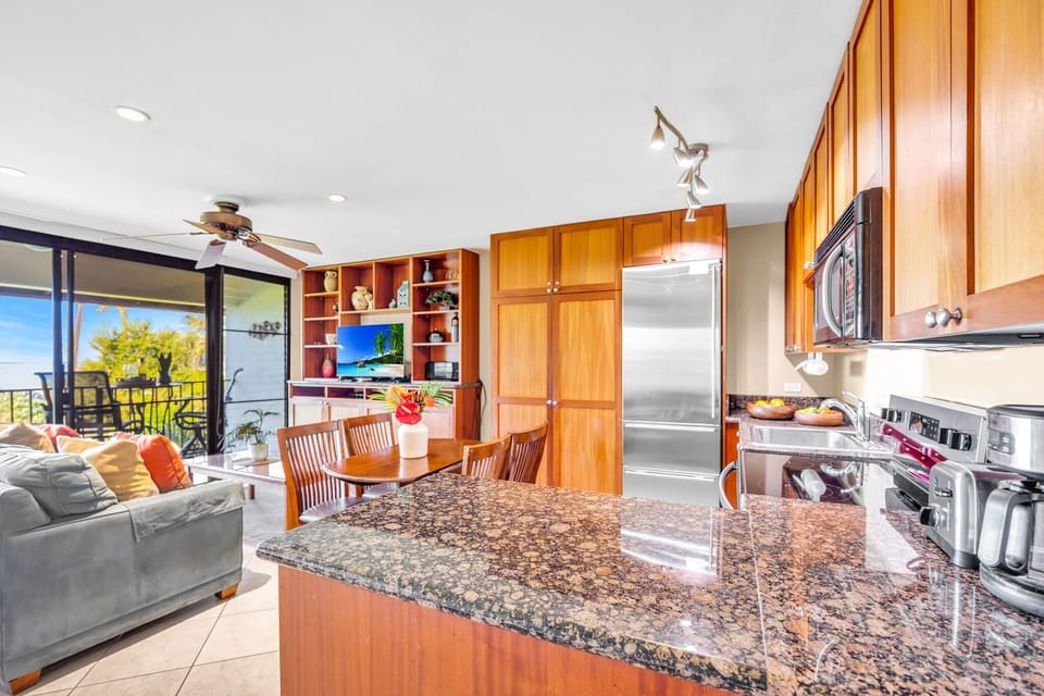 Experience an inviting open-concept layout where the kitchen's polished granite surfaces meet a comfortable living area, complete with vibrant décor and easy access to the outdoor lanai.