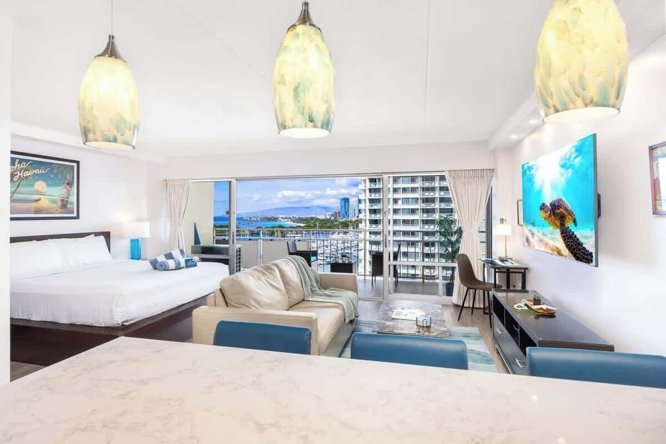 Cozy studio apartment with a plush king bed, pull-out sleeper sofa, and a stunning private balcony view of the harbor and cityscape.