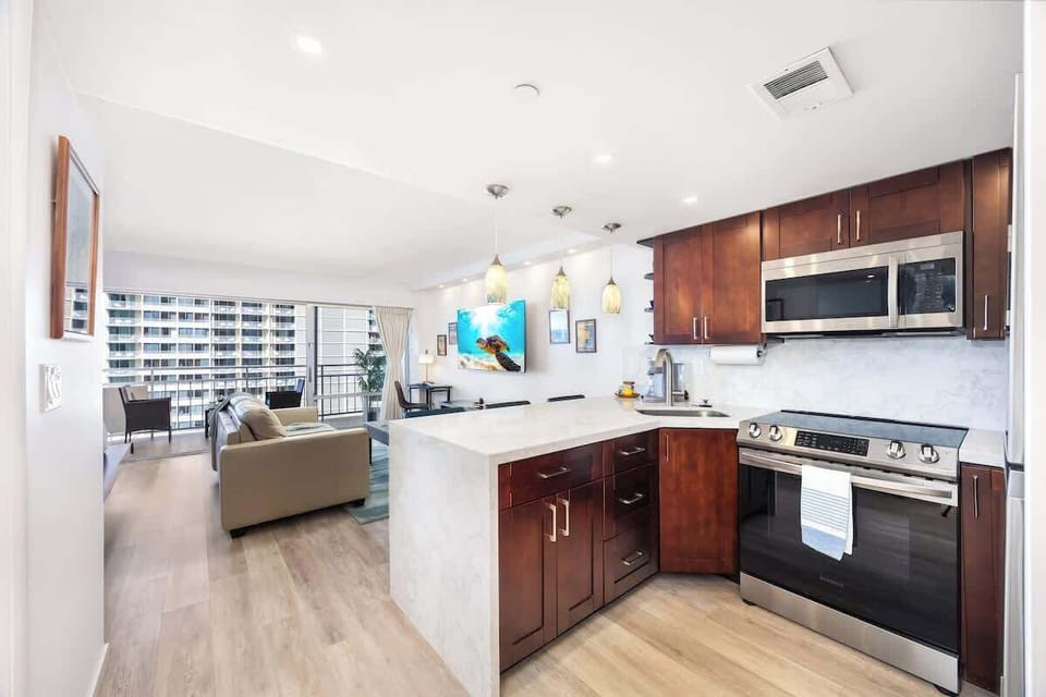 Fully equipped modern kitchen featuring a sleek glass cooktop stove/oven and a marble countertop that seamlessly integrates into the open living area of the studio.