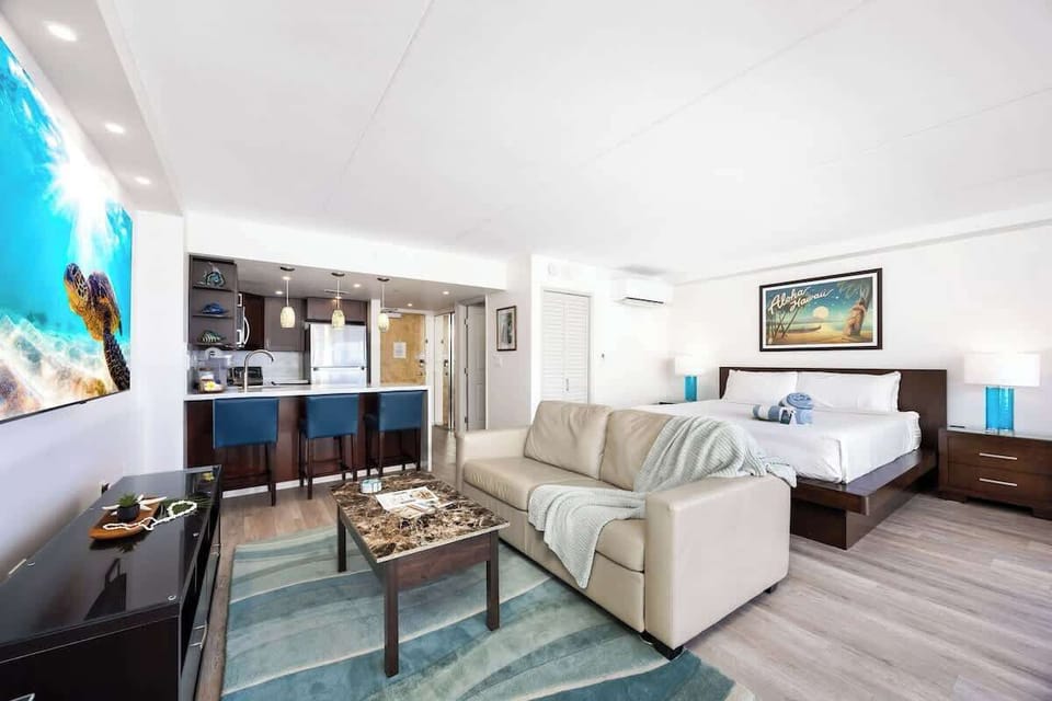 Relax in your modern studio featuring a king-size bed, a kitchen with bar seating, a sleeper sofa, and a 65" Smart TV.