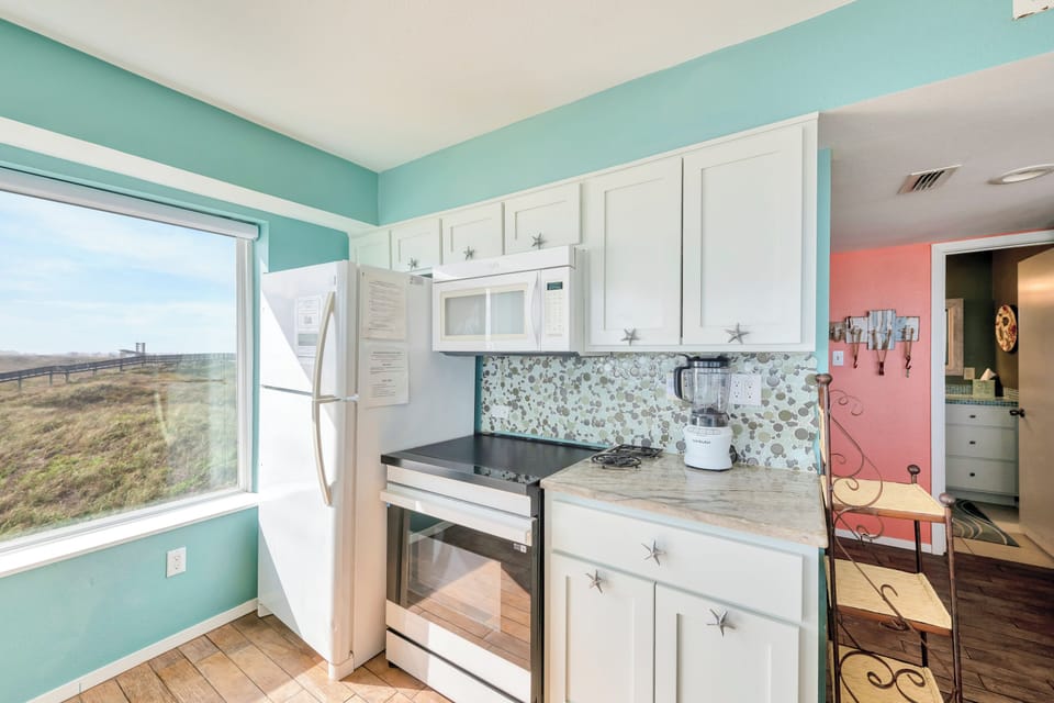 Your fully equipped kitchen features coastal charm with starfish-adorned cabinets and stunning natural views through the large window.