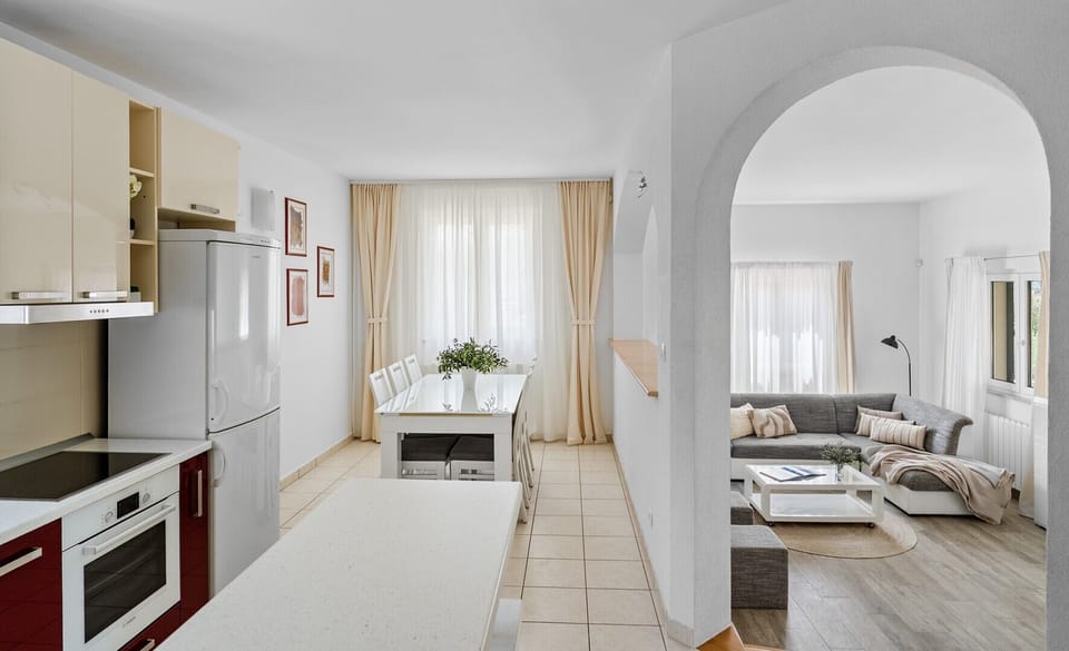 Kitchen view showing the open-plan dining and living area via steps and archway.