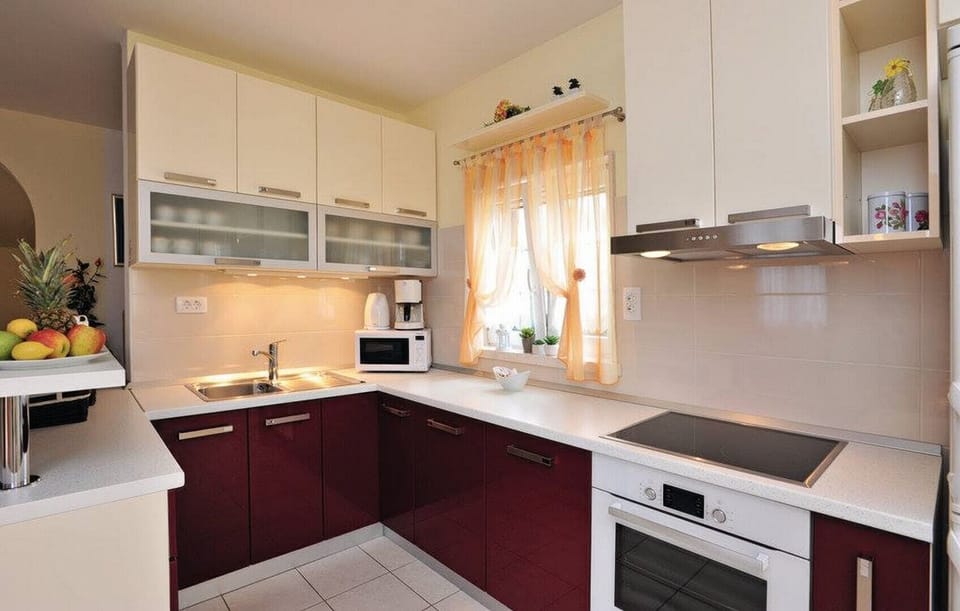 Fully equipped kitchen in one of the apartments features rich red lower cabinets and a functional layout for preparing meals.