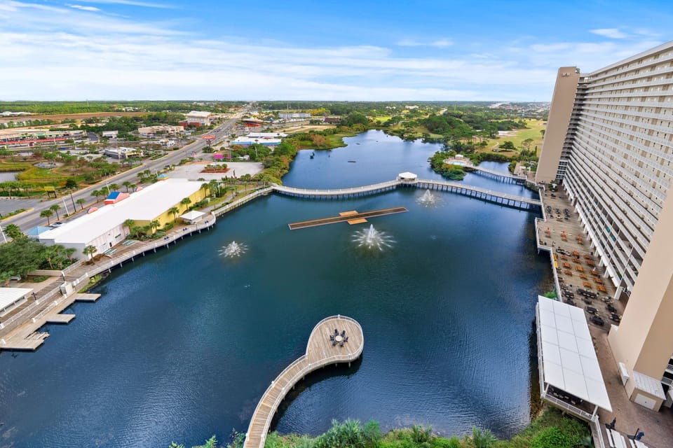 View of the waterfront with fountains and a curved boardwalk from a high-rise balcony
