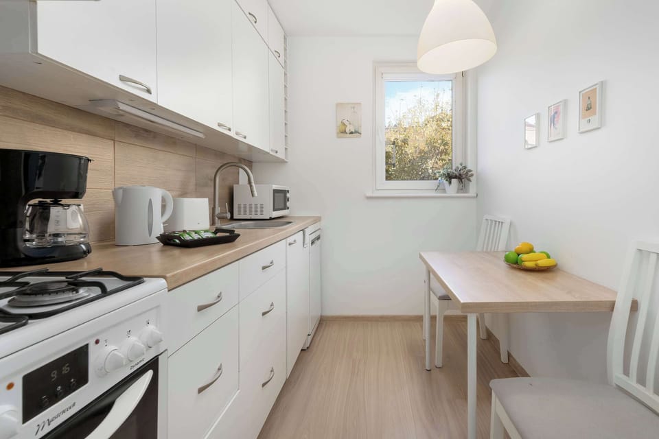 A modern kitchen with white furniture and a dining table with chairs.