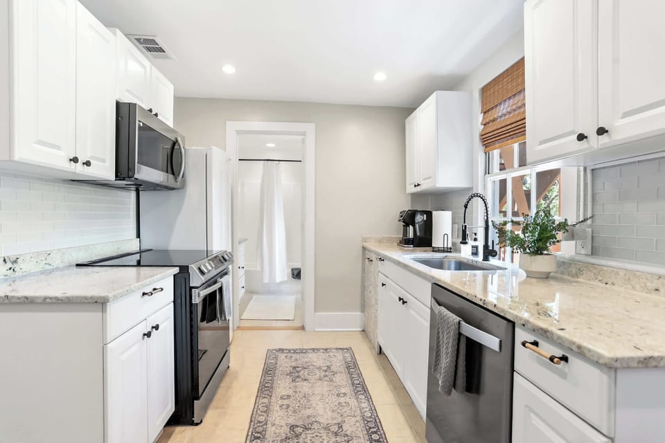 Full kitchen view from entry showing the galley layout, recessed lighting, subway tile, and ample counter space for meal prep.