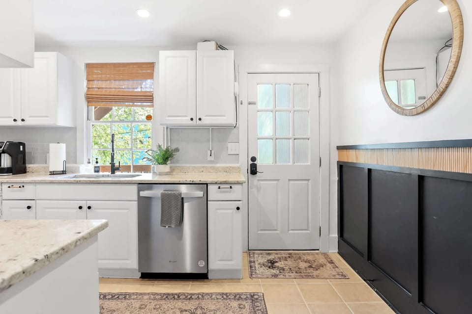 Kitchen entry view with back door access, stainless dishwasher, and woven accent mirror. Keyless entry provided on both front and back doors.