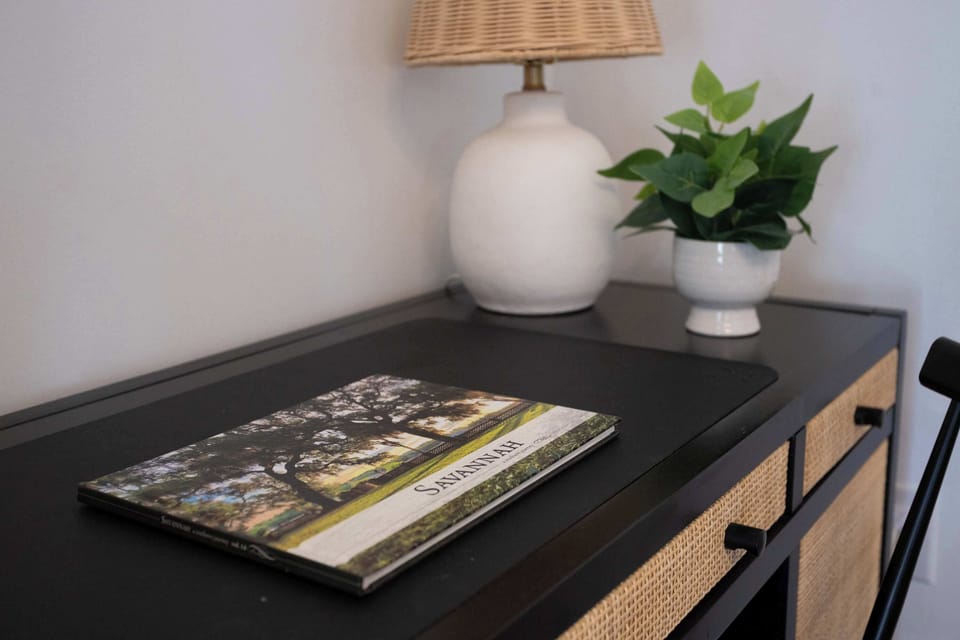 Curated desk with Savannah coffee table book, rattan lamp, and greenery. Local touches throughout to help you explore the city.