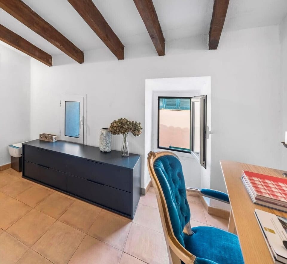 Bright room with exposed wooden beams, modern furniture and a desk by the window, ideal as a workspace or reading corner within the home.