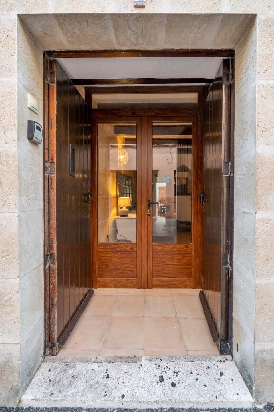 Main entrance of the house with double wooden doors and a stone frame, featuring traditional Mallorcan architecture and direct access to the interior hall.