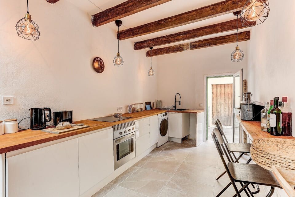 Bright kitchen with wooden countertops, built-in appliances and exposed beams, featuring a bar area with stools and direct access to the outdoor patio.