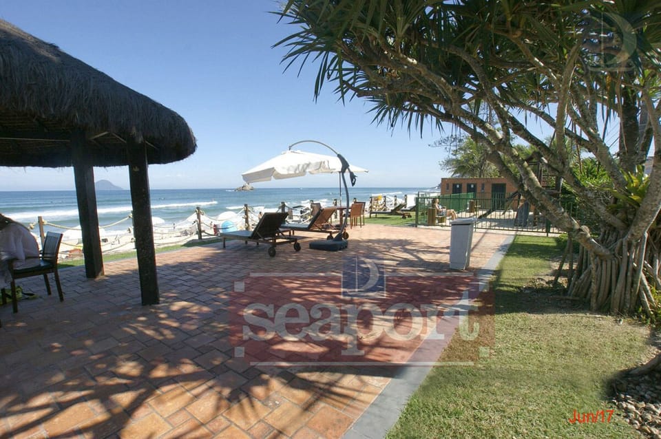área do condomínio frente ao mar, com banheiros, chuveirão, quiosque, cadeiras
