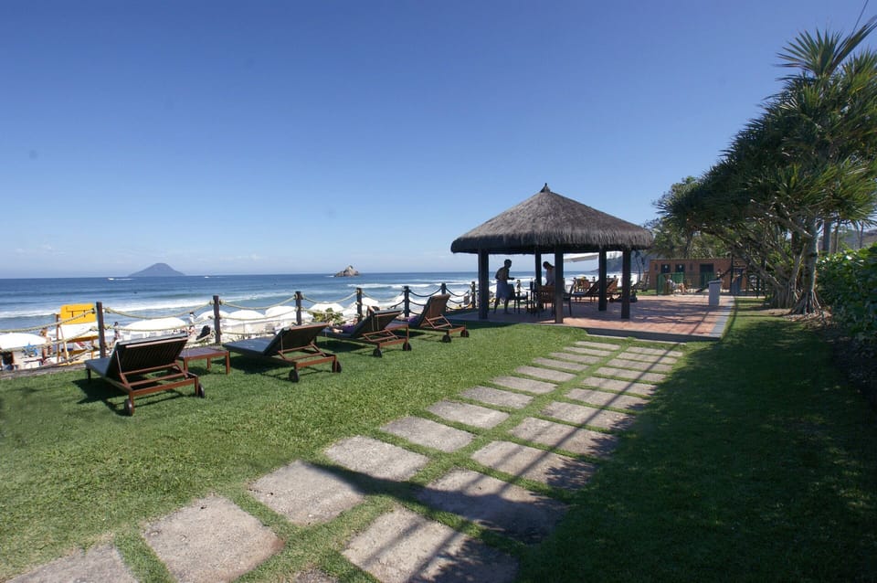 área do condomínio frente ao mar, com banheiros, chuveirão, quiosque, cadeiras