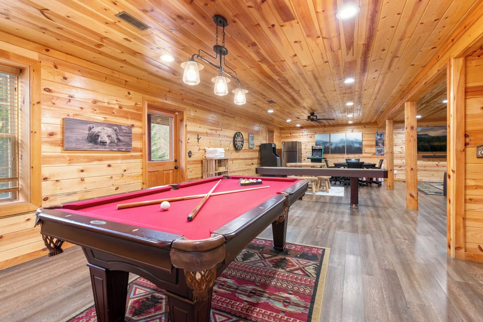 Rustic game room with pool, shuffleboard, and arcade—cabin fun!