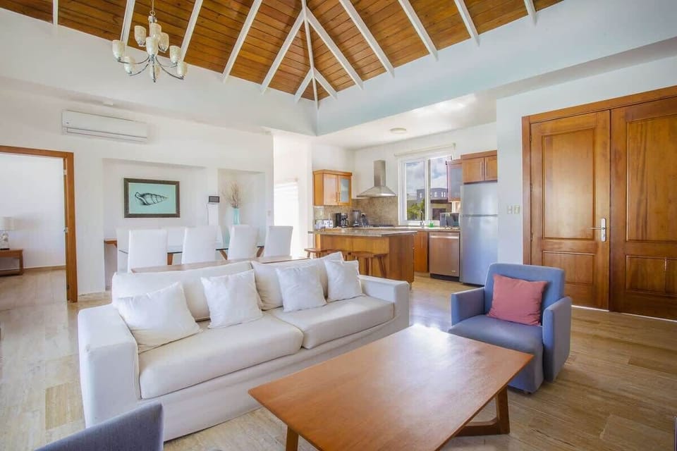 Airy living area with vaulted wood ceilings, cozy seating, and a seamless indoor–outdoor feel.