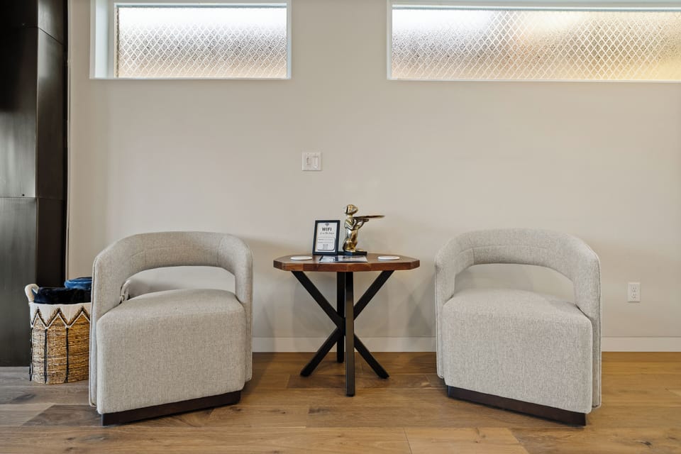A warm welcome awaits—sink into two plush chairs by the elegant entry table, where gold details set the tone for your luxurious Boise getaway.