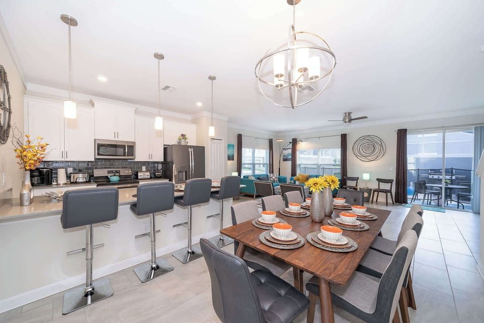 Open-concept kitchen and dining area with modern lighting and seating for eight.
