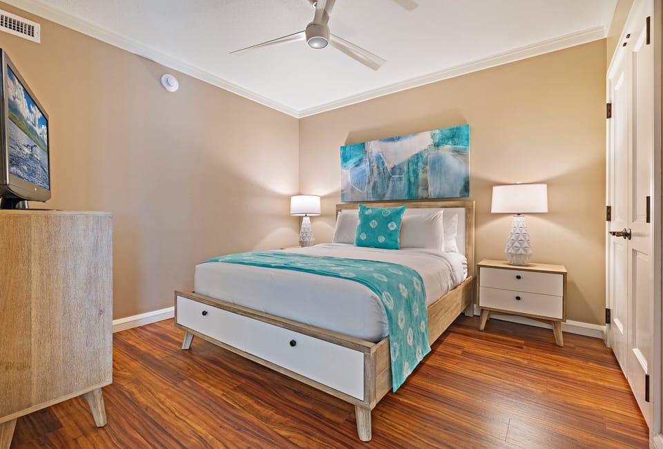 Unwind in a stylish bedroom with a chic upholstered headboard, calming aqua accents, and warm lighting for a tranquil retreat