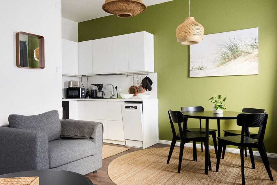 The apartment features an eye-catching olive green accent wall that brings life and warmth to the space.