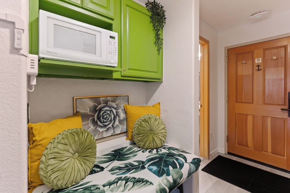 Unwind in your cozy nook with tropical vibes, bright green cabinets, and a convenient microwave for easy meal prep.