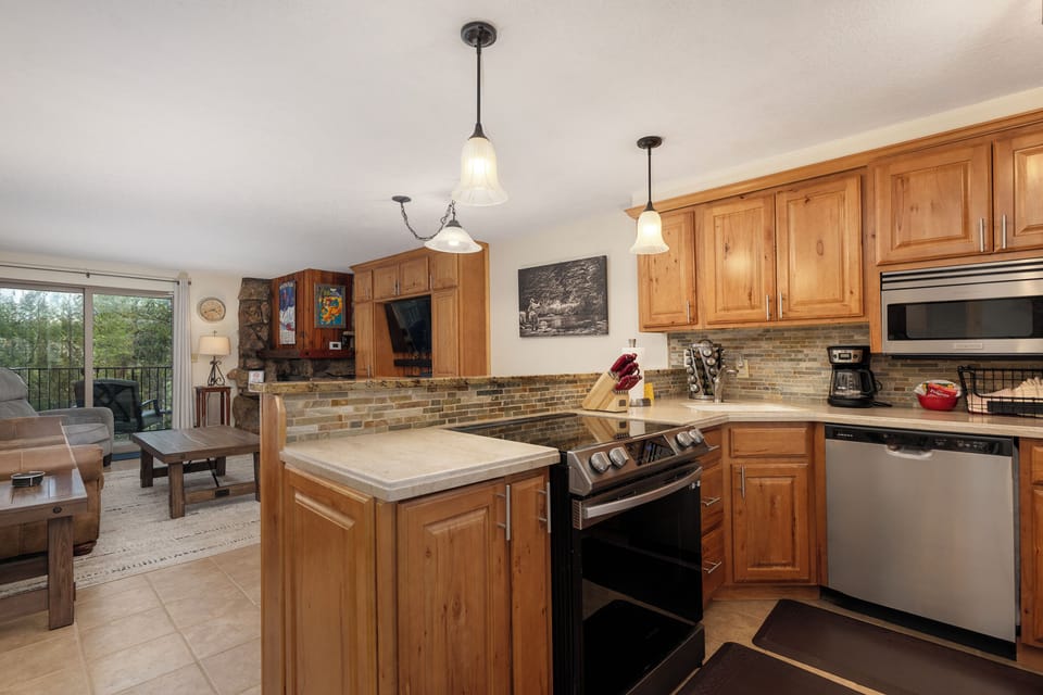 Your fully equipped kitchen features warm wood cabinets, modern appliances, and a cozy breakfast bar for preparing memorable meals together.