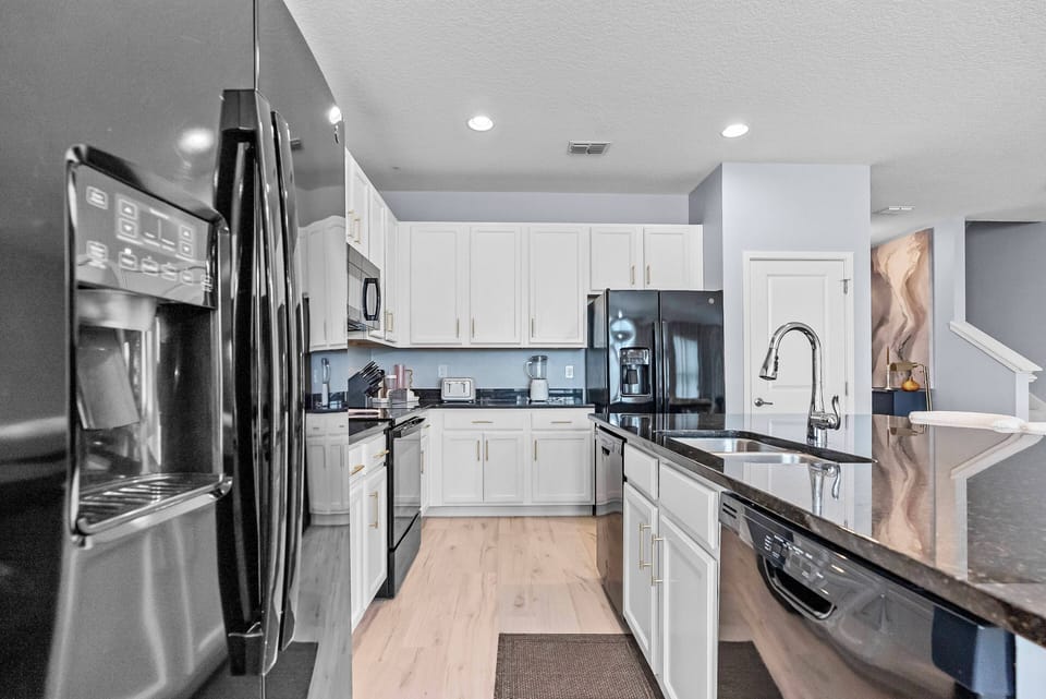Welcome to a stunning kitchen with sleek black appliances and white cabinets that beautifully contrast with warm wooden floors.