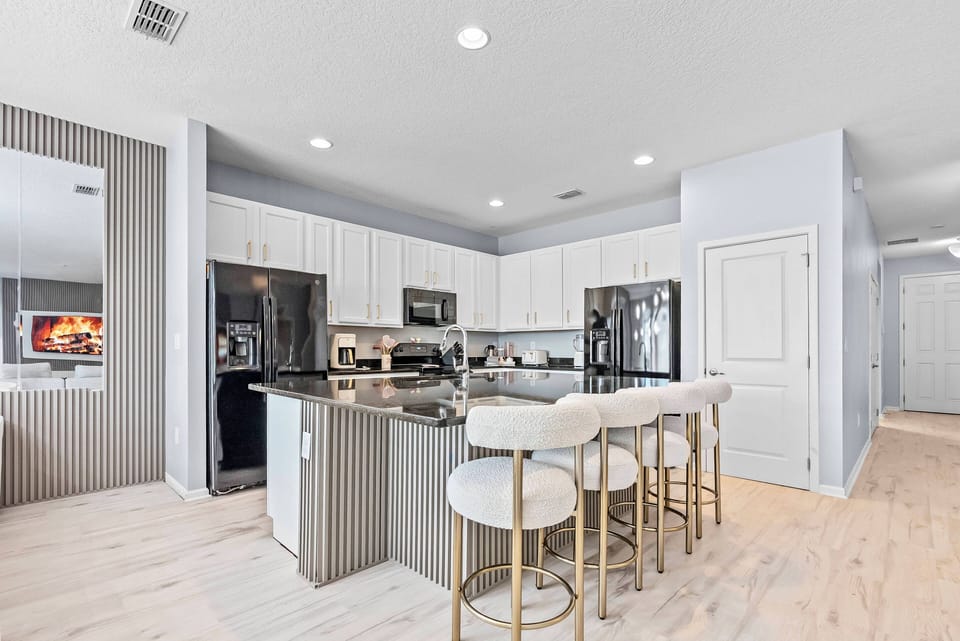 Enjoy a delightful kitchen with sleek black appliances and elegant white cabinetry. The spacious island with stylish bar stools is perfect for casual gatherings, while soft blue walls provide a refreshing backdrop for your.