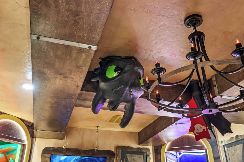 Experience a unique ambiance with a whimsical ceiling accent that ignites curiosity. Rustic wooden beams and an elegant chandelier create a warm atmosphere, ideal for gathering with friends and family amidst playful decor.