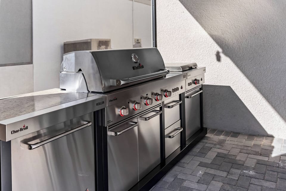 Enjoy your dedicated grilling station, complete with a sleek stainless steel barbecue perfect for culinary adventures. Its modern design and polished surfaces blend seamlessly with textured pavers for a stylish outdoor experience.