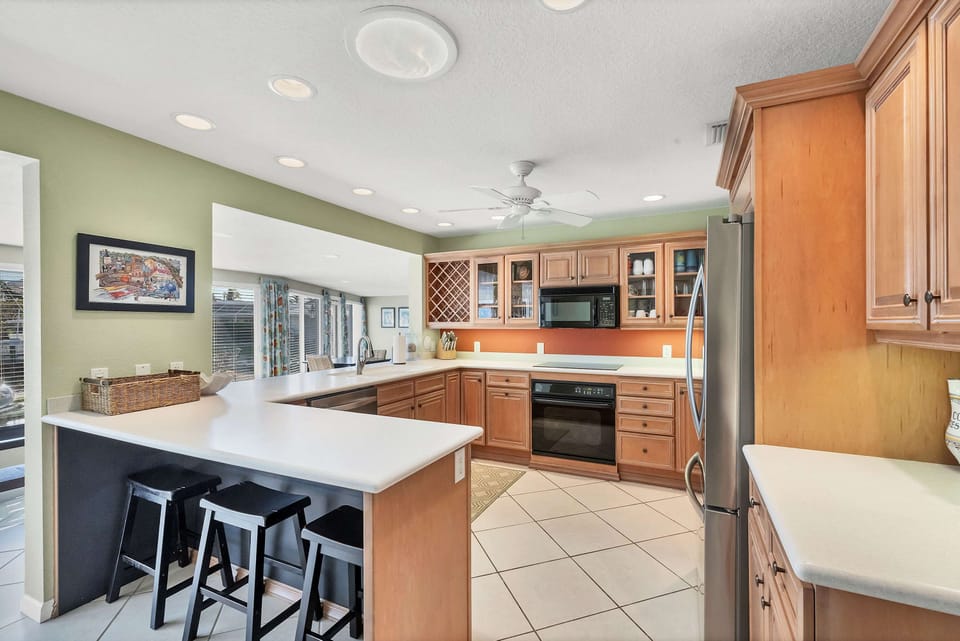Fully equipped modern kitchen with breakfast bar and corian countertops in Longboat Key rental.