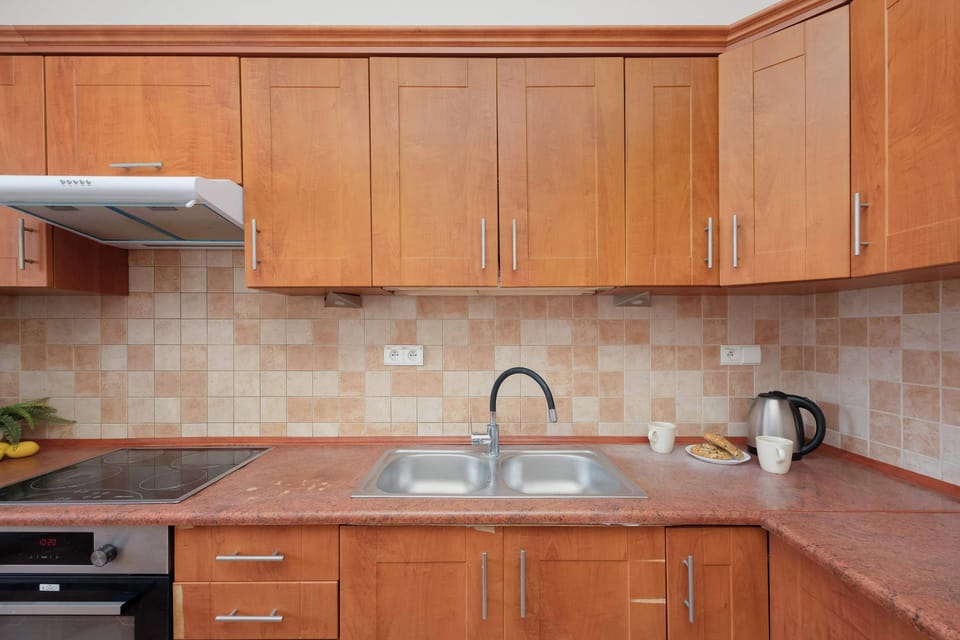 Close-up of the kitchen counter and sink area with a stove and storage cupboards. The room has a cozy, homely atmosphere.