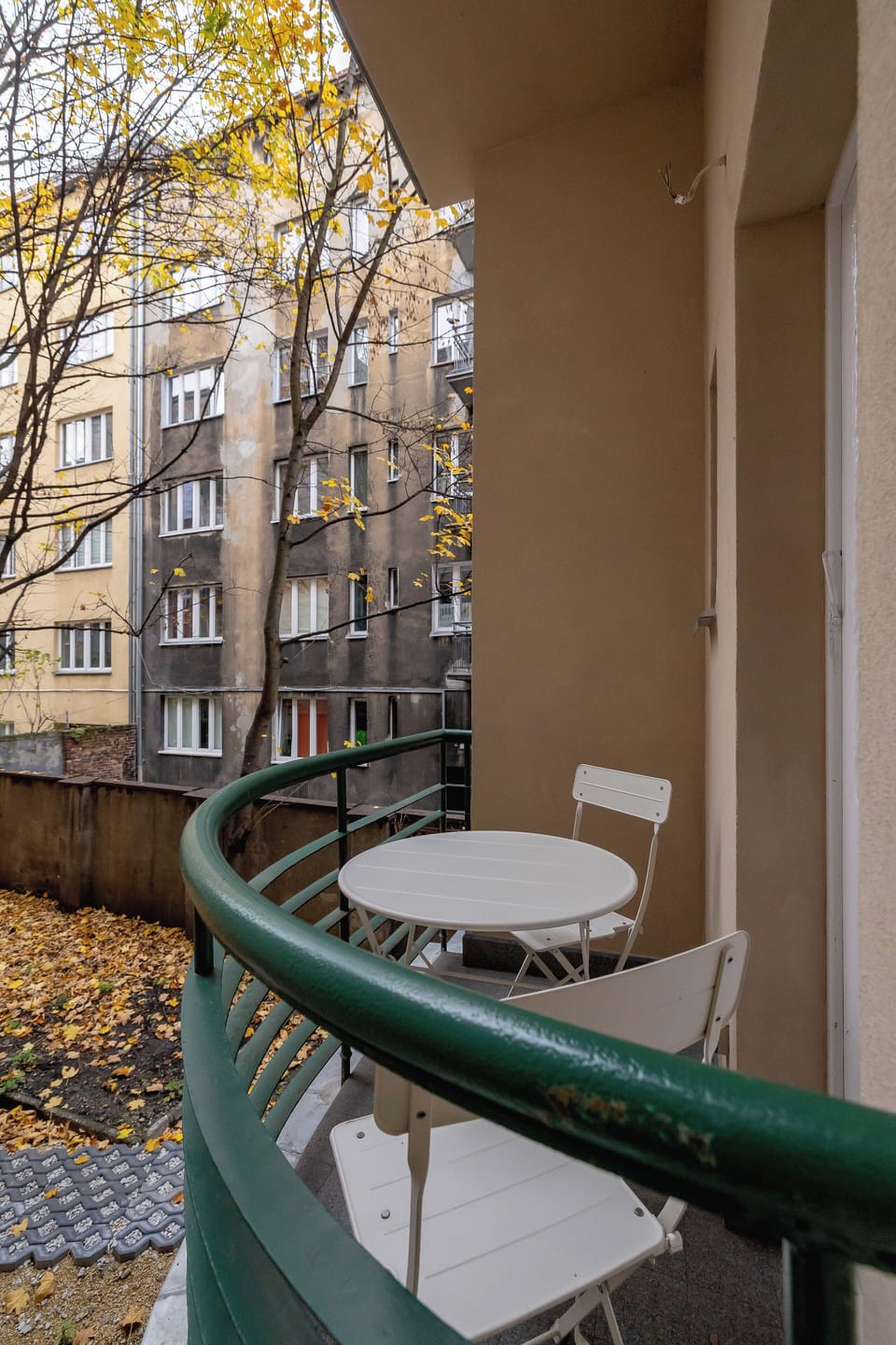 A balcony with a small green railing and a cozy setup for enjoying outdoor moments.