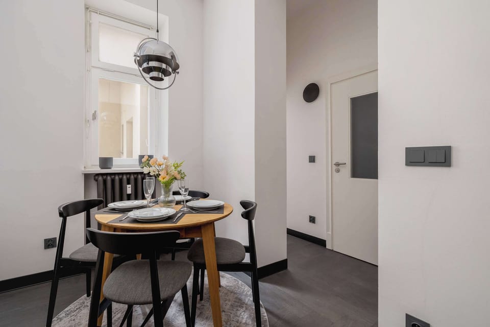A view of the open living space connecting the lounge area and kitchen, with elegant lighting above.
