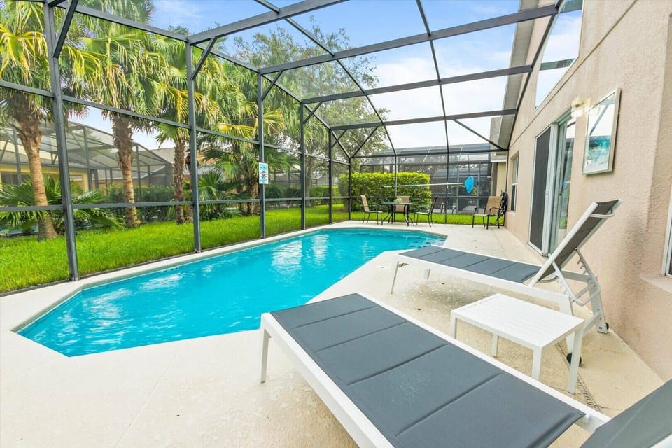 Step into your own private oasis with a crystal-clear pool framed by lush greenery, perfect for sun-soaked afternoons. Relax on modern lounge chairs while enjoying the tranquil view through the spacious screened enclosure.
