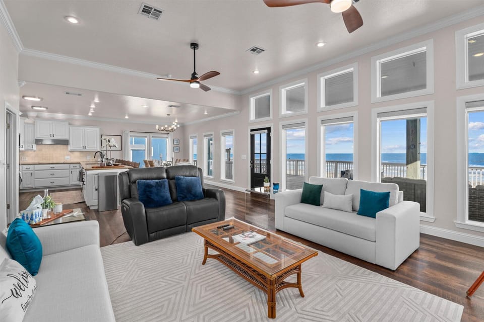Expansive living space with panoramic windows, ceiling fans, and open layout connecting to kitchen and dining areas.